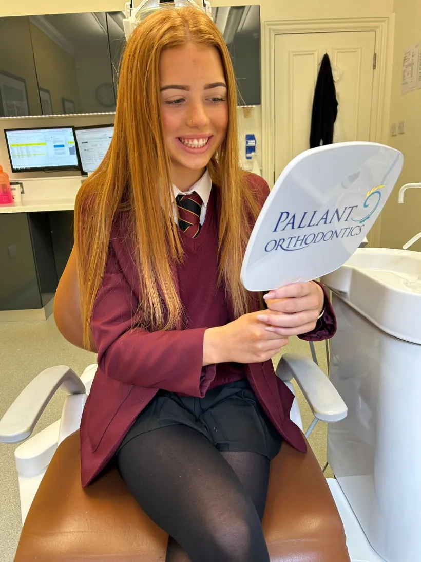 A happy young patient admiring her new smile at Pallant Advanced Dentistry